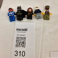Five Lego minifigures in a row with a MaxSold QR code card