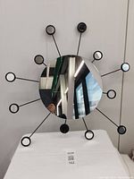 Front view of Ikea sunburst style mirror with central round mirror and 12 small round mirrors on black metal rods