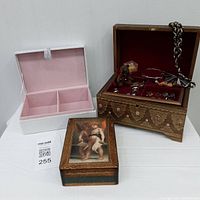Photo showing three jewelry boxes: the Florence wood box partially open displaying jewelry and a white and pink Ralph Lauren box open showing interior compartments, and a small box with cherub image lid.