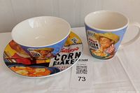 Full view of the Kellogg's Corn Flakes breakfast set including bowl, cup, and plate with vintage advertising graphics.
