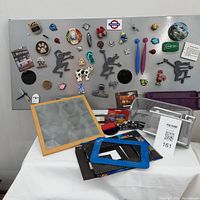 Wide view of the magnetic board filled with various magnets in novelty and colorful designs. Several mesh baskets and frames are on or near the board.