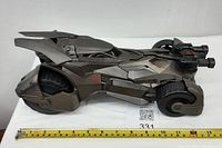 Side view of the Batmobile toy alongside a measuring tape showing approximately 13 inches length