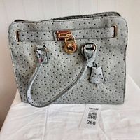 Front view of grey ostrich leather Michael Kors tote with lock detail and two handles