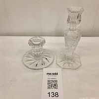 Photo showing two Pinwheel glass candle holders side by side, one taller with geometric faceted shape and octagonal base, one shorter round with pinwheel cut design.