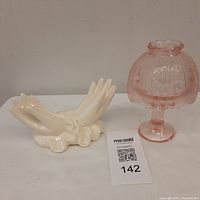 Photo of cream-colored ceramic Midas hand motif card holder and pink floral motif glass fairy lamp side by side