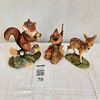 All three porcelain figurines grouped: red squirrel, Cedar Waxwing bird, and fawn.