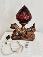 Front view of vintage Roman gladiator chariot lamp with red glass shade, showing entire lamp and power cord with switch.