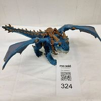 Blue Shansy Bayala dragon action figure with detailed blue scales, spikes, yellow eyes, and brown saddle seen from side.