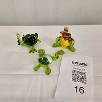 Three glass frog figurines displayed on a white background showing all pieces in the set.