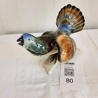 Front side view of porcelain wild game bird figurine showing extended wing and open beak