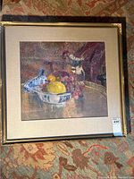 Framed oil painting on fabric depicting a still life with fruit and blue and white ceramic pieces, signed by Alice Pommec.