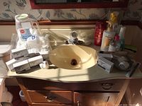 Sink countertop with multiple Dove soap boxes, bag of cotton balls and container of Epsom salts arranged around bathroom sink.