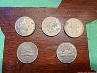Lot of 5 Canadian Silver Dollar coins including 3 with provincial designs laid out on wooden surface with green tape edges visible.