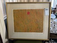 Front view of framed etching leaning against a striped wallpapered wall