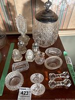 Full view of the collection including cookie jar with silver plate lid, perfume bottle, salt and pepper shakers, small bowls, and cutlery rests.