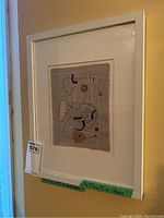 Framed embroidery on burlap showing the full piece and frame against a yellow wall with auction tag visible.