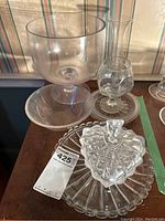 Overview of glassware lot showing large wheat-etched Laligest bowl, trifle bowl, vase, stemmed goblet, serving plate and candy dish.