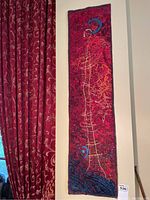 Full view of vertical textile wall hanging mounted next to patterned drapery