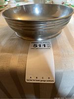 Side view of a round pewter bowl with decorative bands near rim, showing the shape and material.