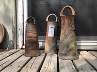Frontal view of three pottery vases showing their weathered condition and looped handles