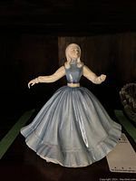 Front view of the Royal Doulton Jennifer HN 2392 porcelain figurine showing the glossy blue dress and extended arms.