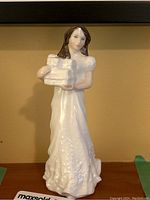 Front view of the Royal Doulton figurine 'Christmas Parcels' with the woman holding parcels, showing detailed dress and face.