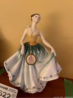 Front view showing figurine holding skirt with tag