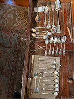 Overhead view of mixed flatware and serving pieces laid out in drawer