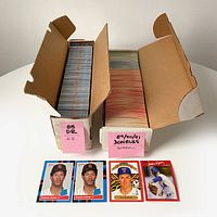 Two open cardboard boxes full of 1988-1991 Donruss baseball cards displayed with four select cards in front: two Roberto Alomar #34 rookie cards, one Nolan Ryan King of Kings, and one standard Nolan Ryan card.