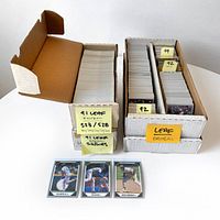 Two open cardboard boxes filled with neatly stacked textured 1991 and 1992 Leaf baseball cards with labels showing 523 of 528 cards and year identifiers. Three displayed cards include Ken Griffey Jr., Nolan Ryan, and Rickey Henderson.