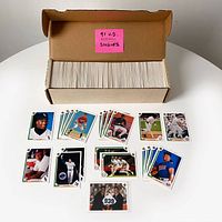 Box containing a large collection of 1991 Upper Deck baseball card singles, with some cards spread out in front showing various player images.