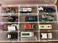 Case of 17 assorted vintage Hot Wheels and Matchbox vehicles arranged in a divided plastic case, showing various models including NASA and USPS themes.