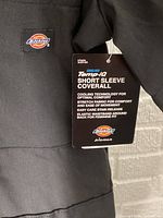 Photo of Dickies label and Temp-iQ cooling short sleeve coverall tag showing features like stretch fabric, easy care, elastic waistband for feminine fit