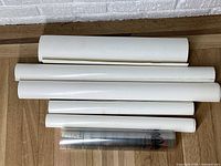 Six rolled posters laid on floor including one transparent with Coca-Cola logo.