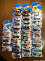 Overview photo showing 36 Hot Wheels die-cast cars in original packaging displayed on a wooden surface.
