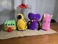 Four Little Monsters colorful plush toys displayed side by side showing front and side details