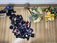Loose LEGO pieces and partial builds on floor: black and purple pieces for Marvel Black Panther set, sand-colored pieces with green lightsaber likely Star Wars Yoda set, yellow parts likely Bowser set.