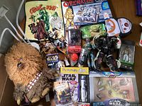 Full view of Star Wars lot featuring plush, flip books, figures, games, and transformation toy