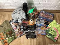 Overview photo showing entire lot: Millennium Falcon playset, Kenner figures, Grogu nightlight, Darth Vader PEZ, Star Wars t-shirts, and various toys and collectibles.