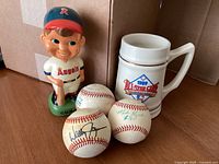 Overview of the lot items: vintage California Angels bobblehead, three baseballs including two signed, and 1989 All-Star Game ceramic stein.
