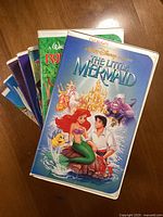 Seven Walt Disney Home Video VHS tapes with visible front cover of The Little Mermaid VHS tape.