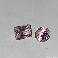 Two light pink faceted gemstones, one rectangular radiant cut and one round cut, shown on a flat surface with good lighting to show color and clarity.