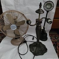 View of all three items: antique-style double lamp, LED lamp, and Holmes desktop fan placed on a white surface with a patterned rug underneath.