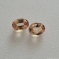 Top view showing two oval peachy/orange colored padparadscha sapphire gemstones.