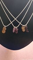 Front view of 3 silver chains with carved tourmaline animal charms including foxes and lobster claw in yellow, pink and rubellite colors.