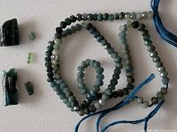 13-inch strand of small faceted blue tourmaline beads coiled with several loose blue tourmaline crystals showing various shapes and natural inclusions.