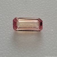 Top view of light pink/peach emerald cut Padparadscha sapphire showing rectangular shape and clear facets.