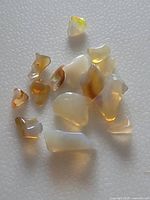 Close-up showing a group of irregular freeform Australian crystal opal stones on a textured white surface.