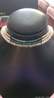 Front view of the pearl choker necklace with three distinct bead layers on display against black jewelry stand.