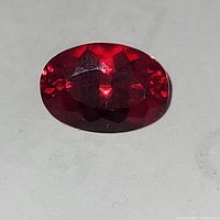 Close-up view of the oval cut red stone showing deep red color and glossy finish